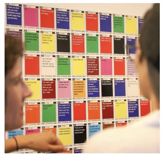 Two people looking at a wall of printed submissions